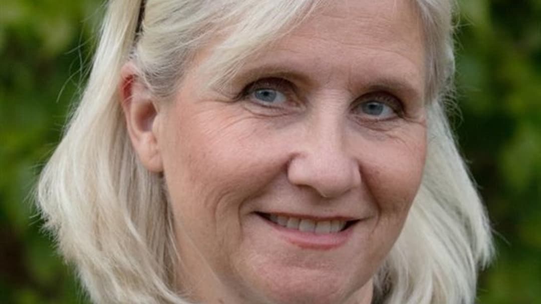 En kvinna utomhus i vit tröja och grå kavaj