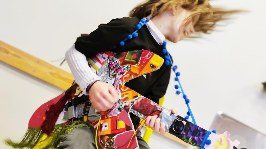 Tjej spelar egenprogrammerad gitarr med kollage