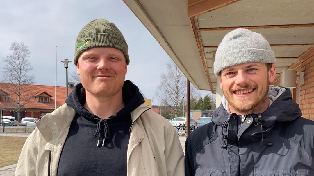 Two persons standing outdoor with caps on their heads.