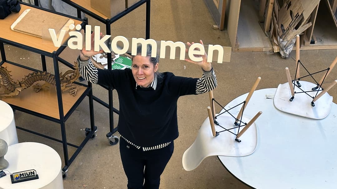 En kvinna håller en skult som det står välkommen på