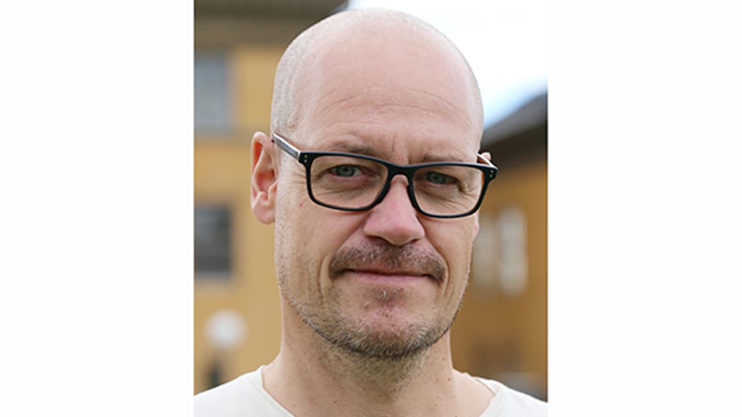 En man i svarta glasögon och rakat huvud.