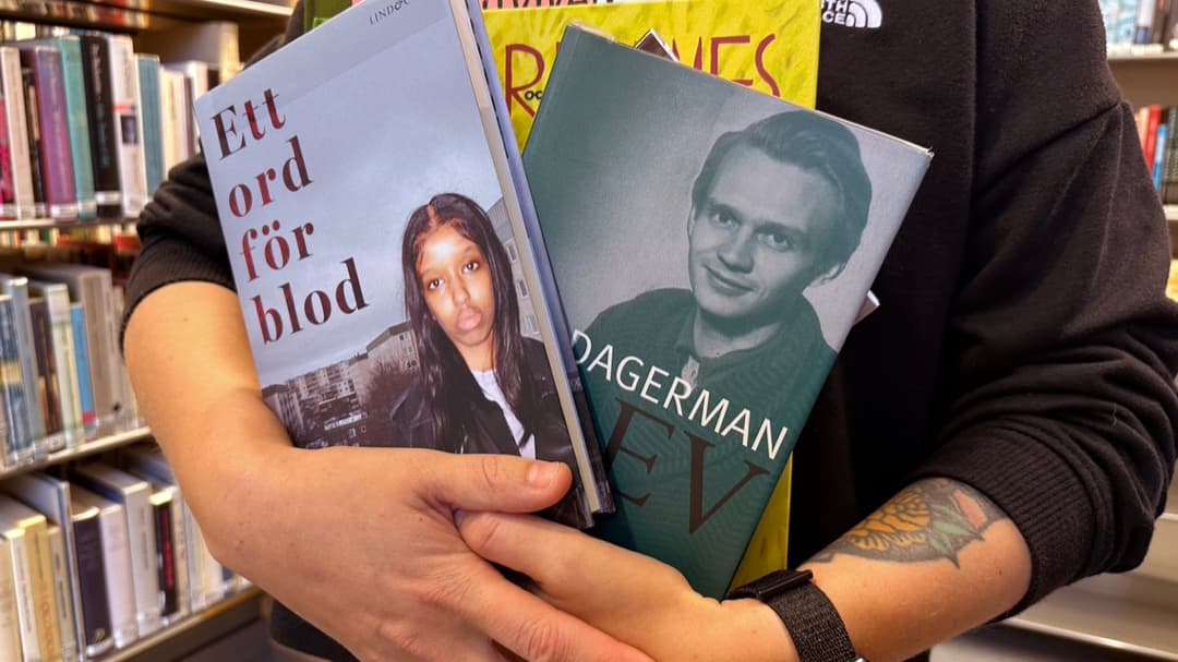 En person håller böcker i sin famn i ett bibliotek