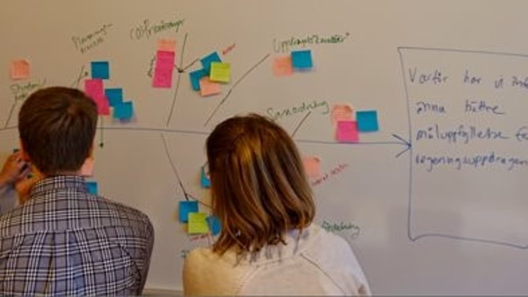 tre personer framför en whiteboardtavla
