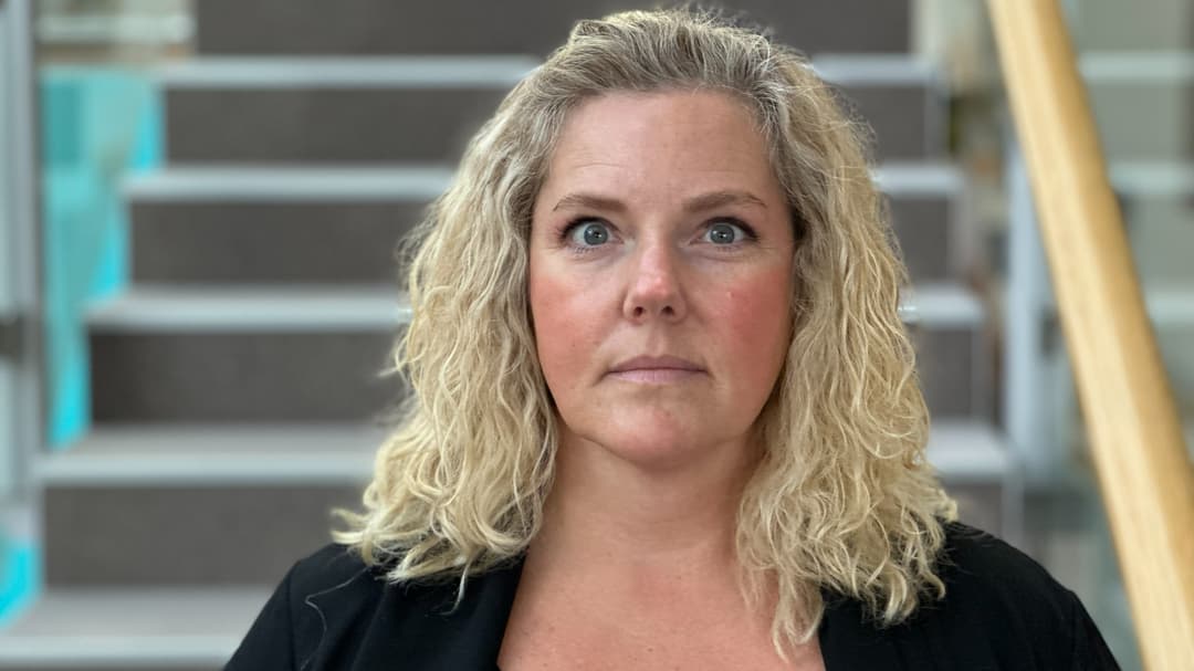 En kvinna med blont hår framför en trappa