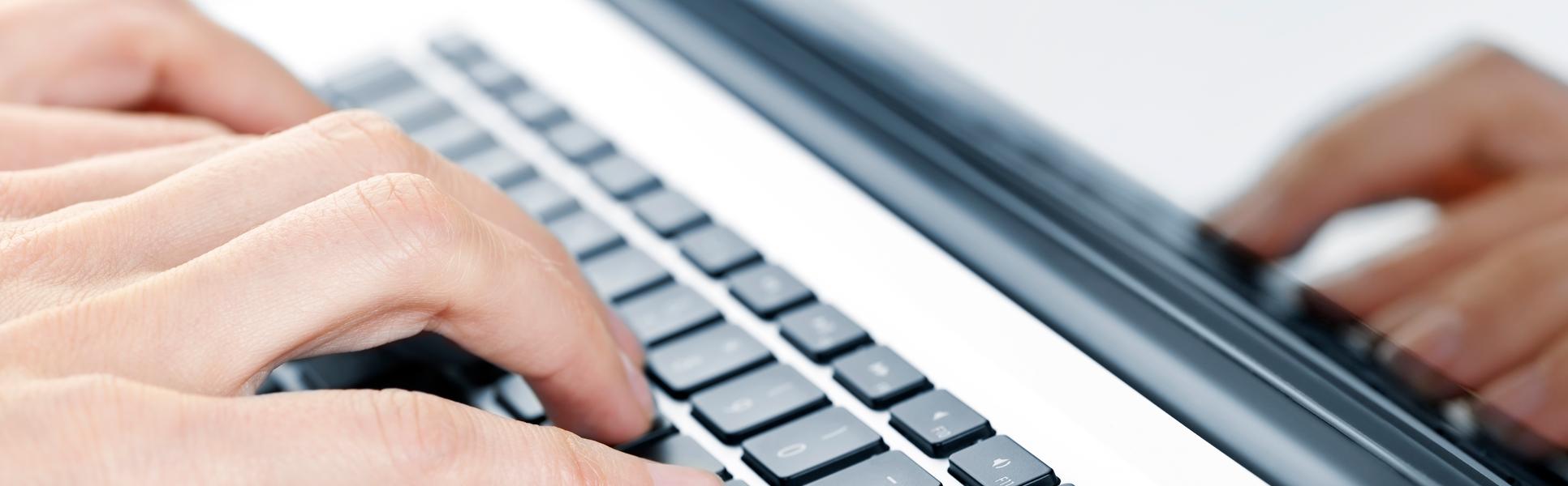 Hands typing on laptop keyboard