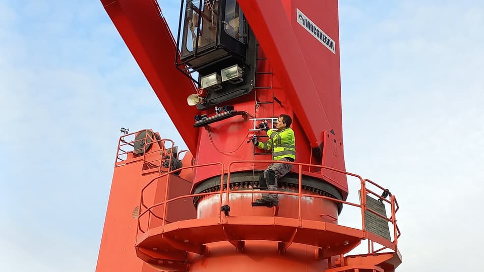 A man is working on a crane at a hangar