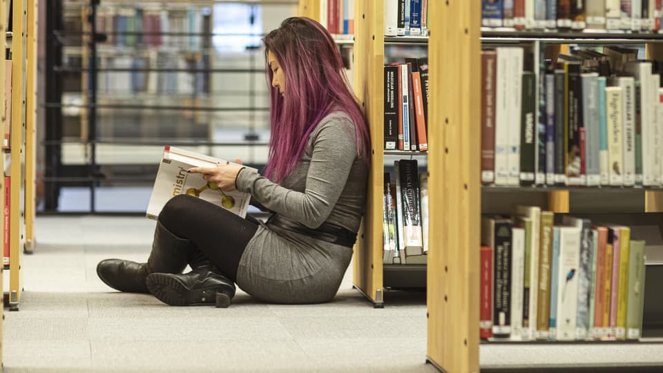 Läsande student bland bokhyllor