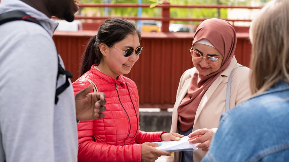 En grupp studenter som står och pratar med varandra utanför campus. 