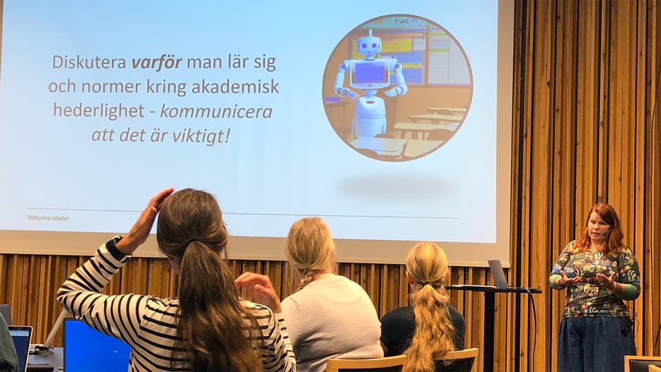 Seminariesituation med en föreläsare, publik och presentationsbild på väggen.