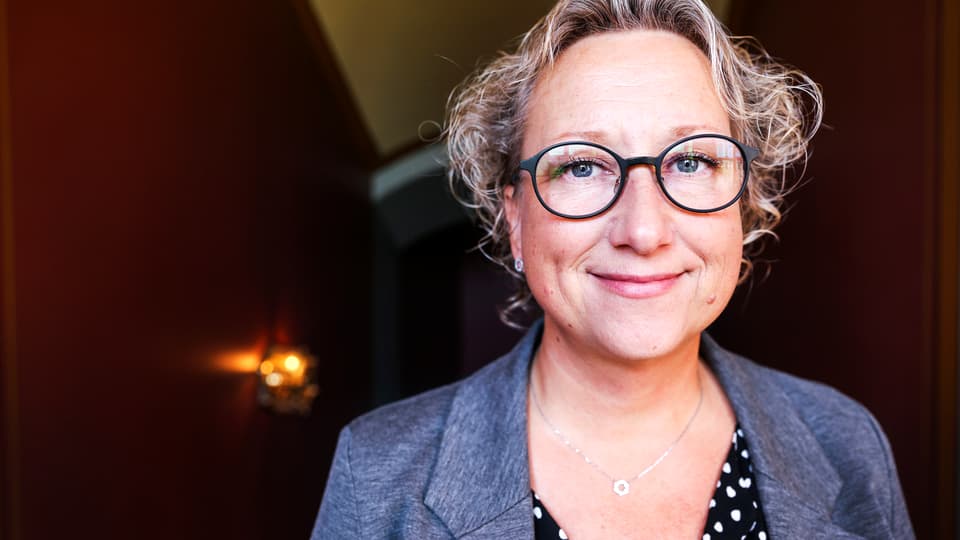 Kvinna med ljust lockigt hår och glasögon.