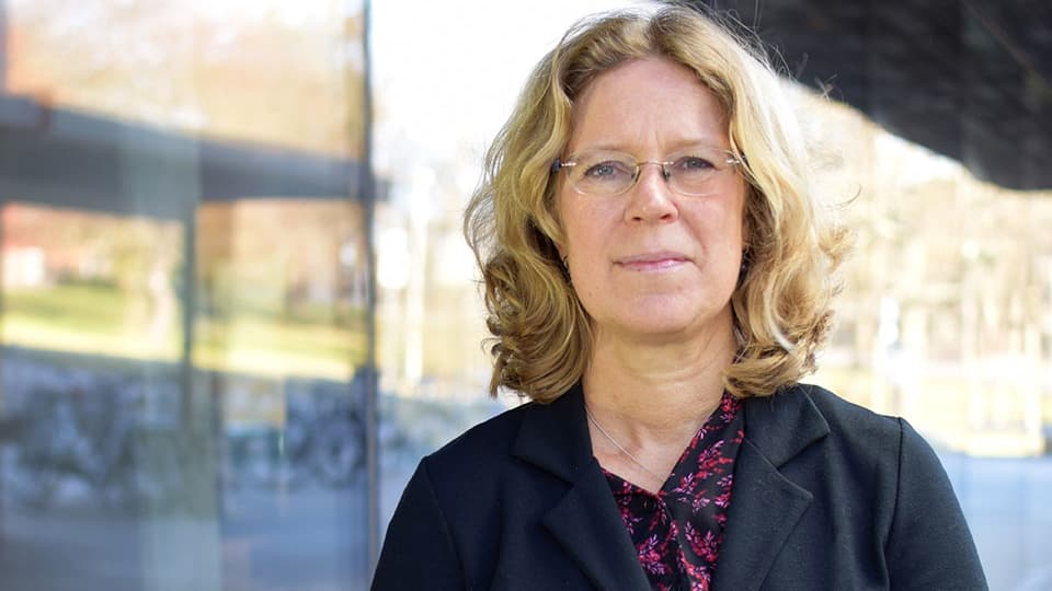Kvinna med blont hår tittar in i kamera