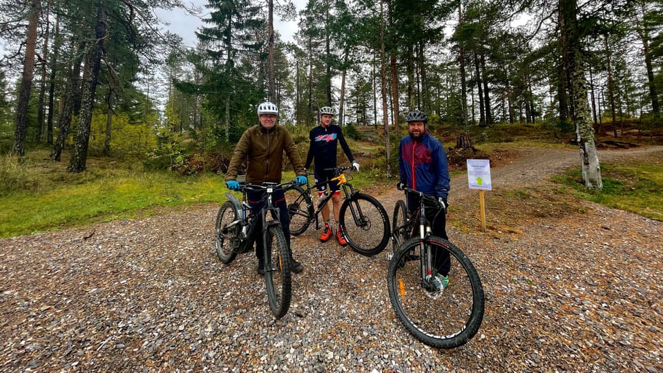Tre personer står med varsin cykel i skogen
