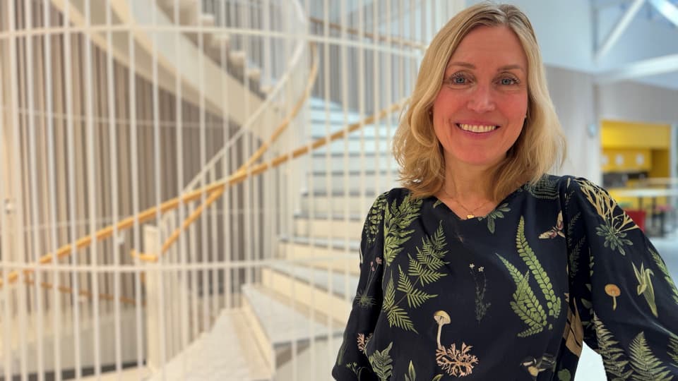 Leende kvinna i svart klänning med gröna blommor