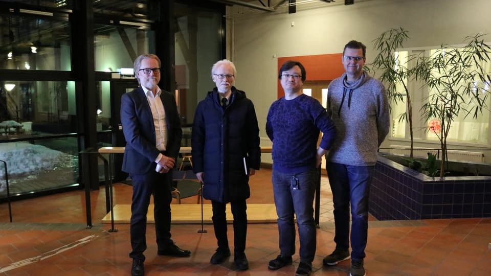 Four men stand in a row.