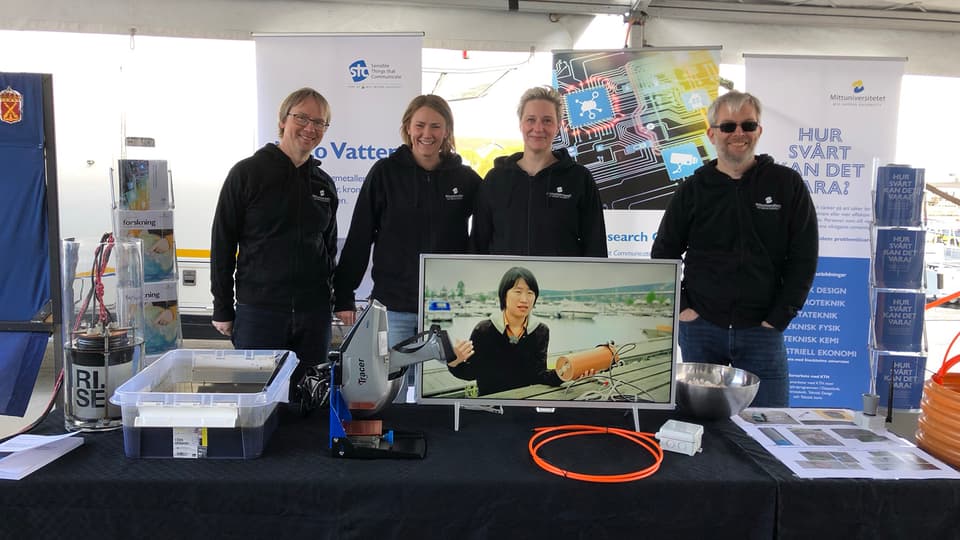 Four people working in Mid Sweden University exhibition stand.
