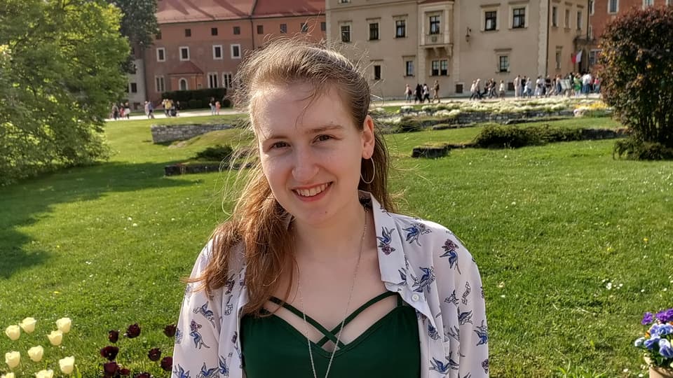 A woman with a green shirt in front of flowers