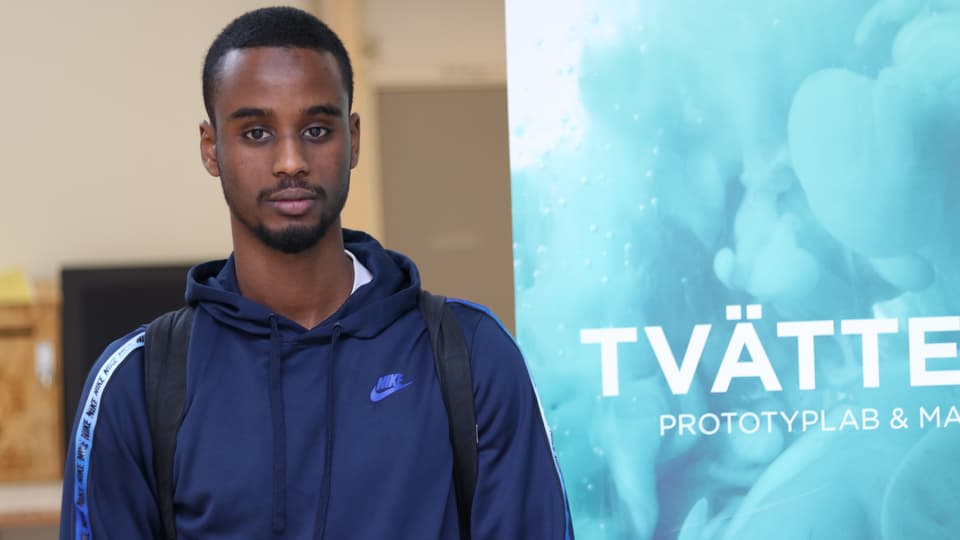 Kille i blå hoodie står framför en rollup