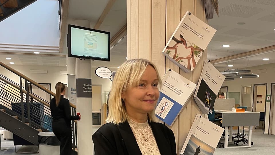 En kvinna i svart kavaj framför sin spikade avhandling