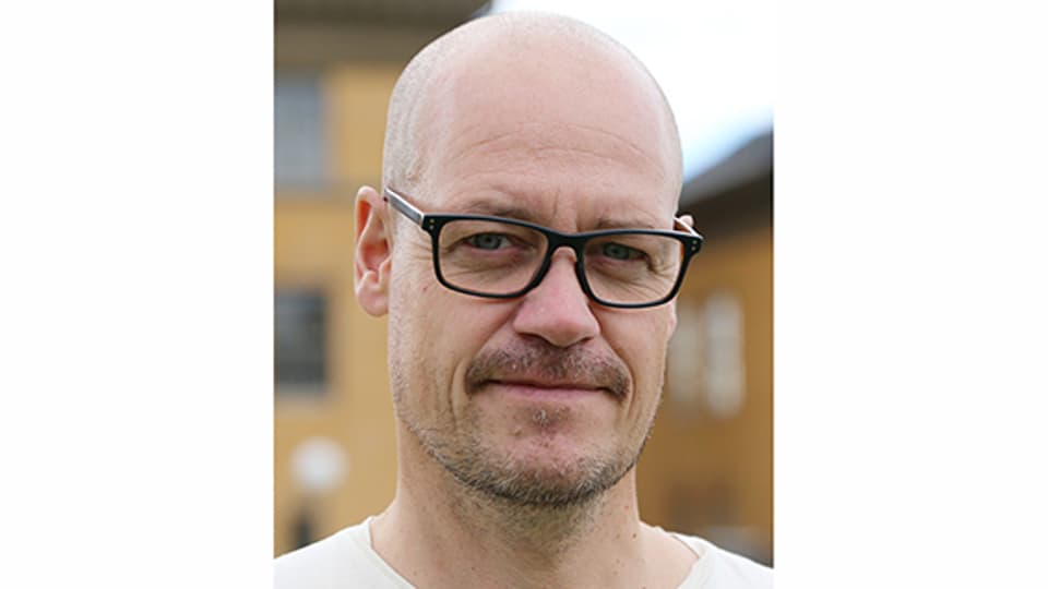 En man i svarta glasögon och rakat huvud.