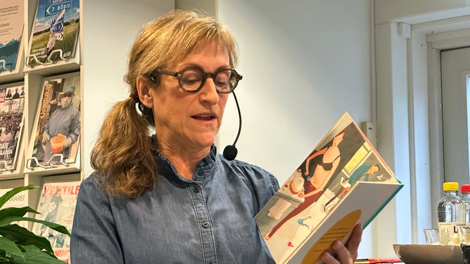 Kvinna läser ur en barnbok i famnen