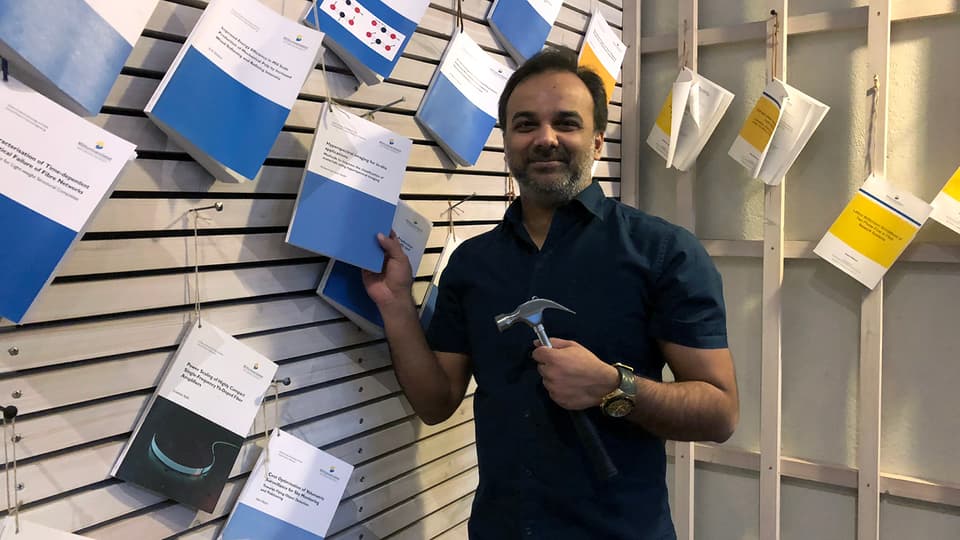 A man standing by a wall with theses nailed up