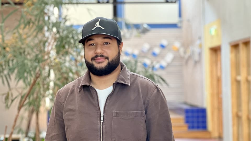 A man with a beard and a hat and a brown sweater