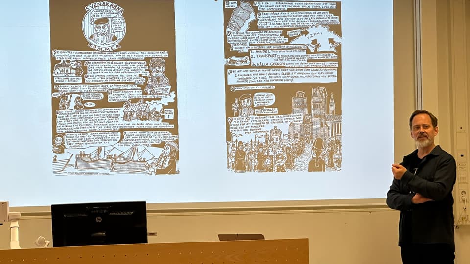 en svartklädd man står framför en projektorskärm