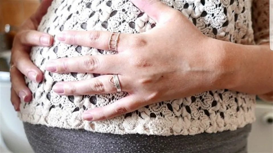 Gravid kvinna med händerna på magen