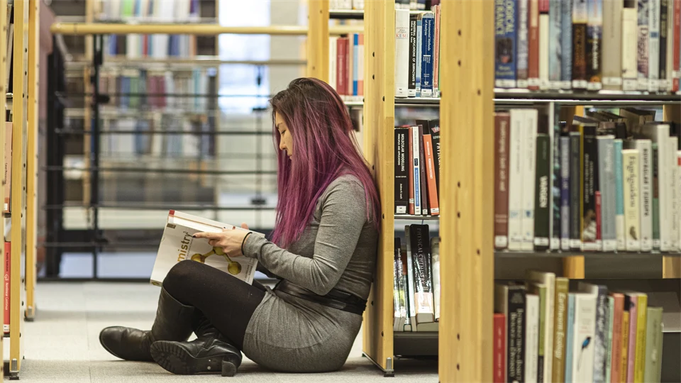 Läsande student bland bokhyllor