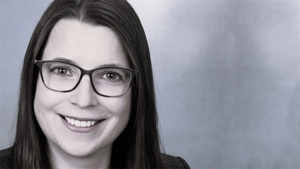 En kvinna med brunt hår och glasögon ler