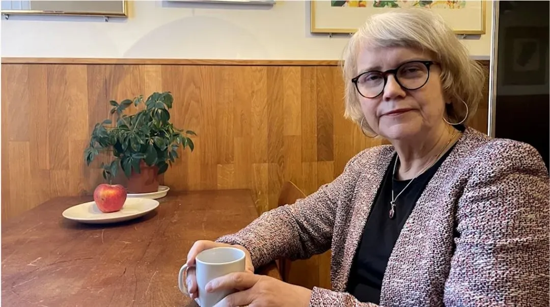 En kvinna med glasögon som håller i en kaffekopp