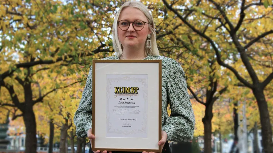 En tjej med som står utomhus och håller i ett inramat pris