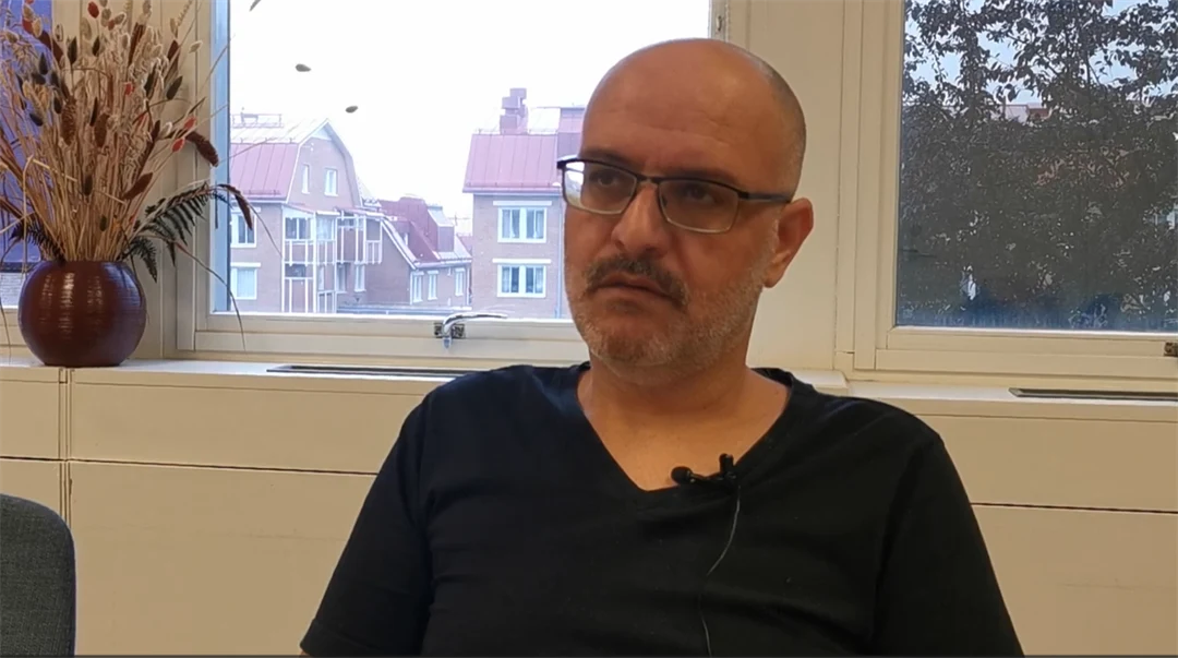 Man klädd i glasögon och svart tröja blir intervjuad