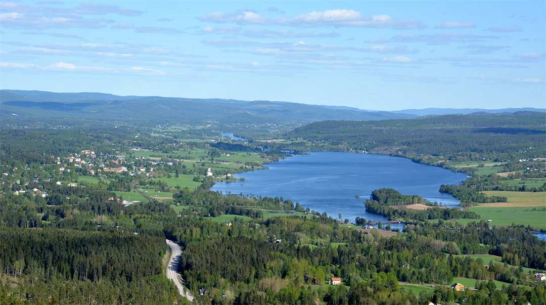 Landskapsbild med gröna berg, ängar och en sjö