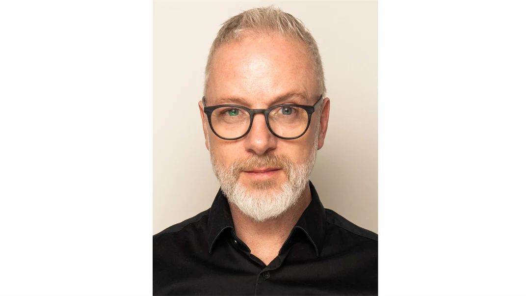 En man med glasögon, skägg och kort hår.