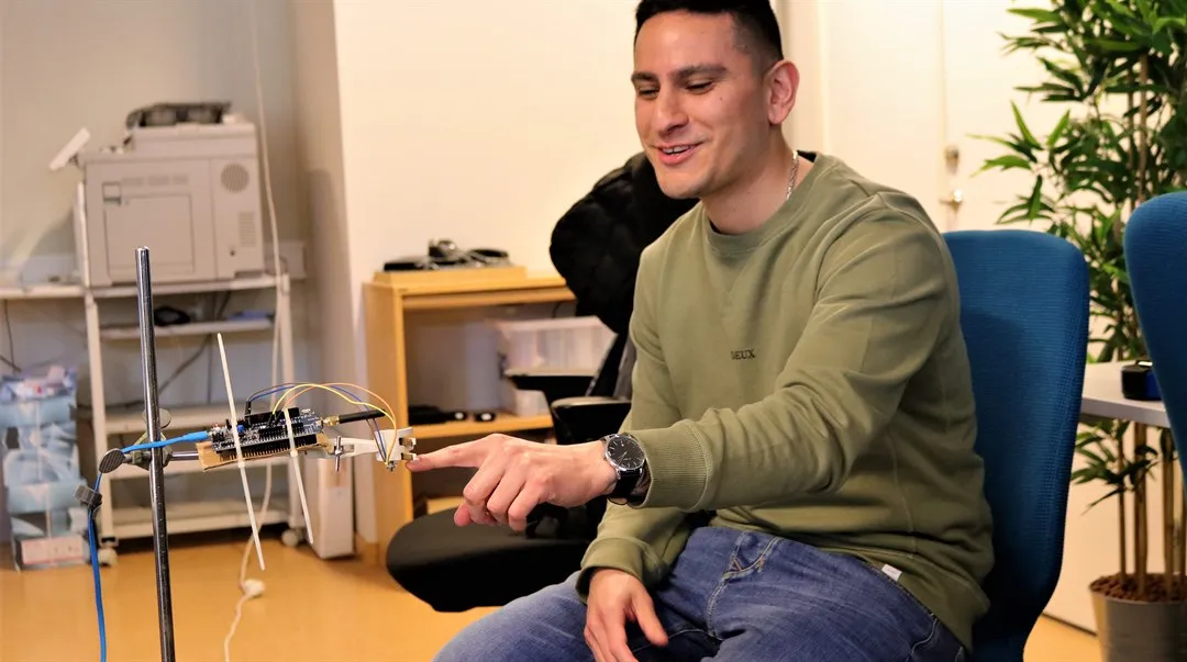 En man sitter ner och pekar på en lasersensor