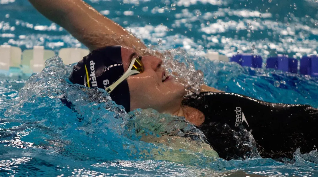 En kvinna som simmar ryggsim.