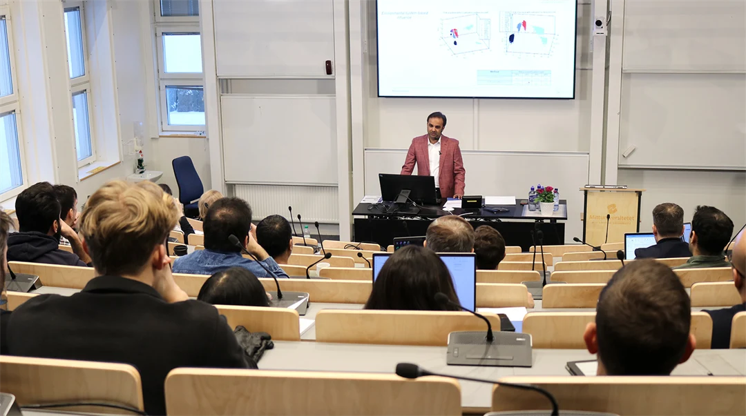 En man står och föreläser i en gradängsal.