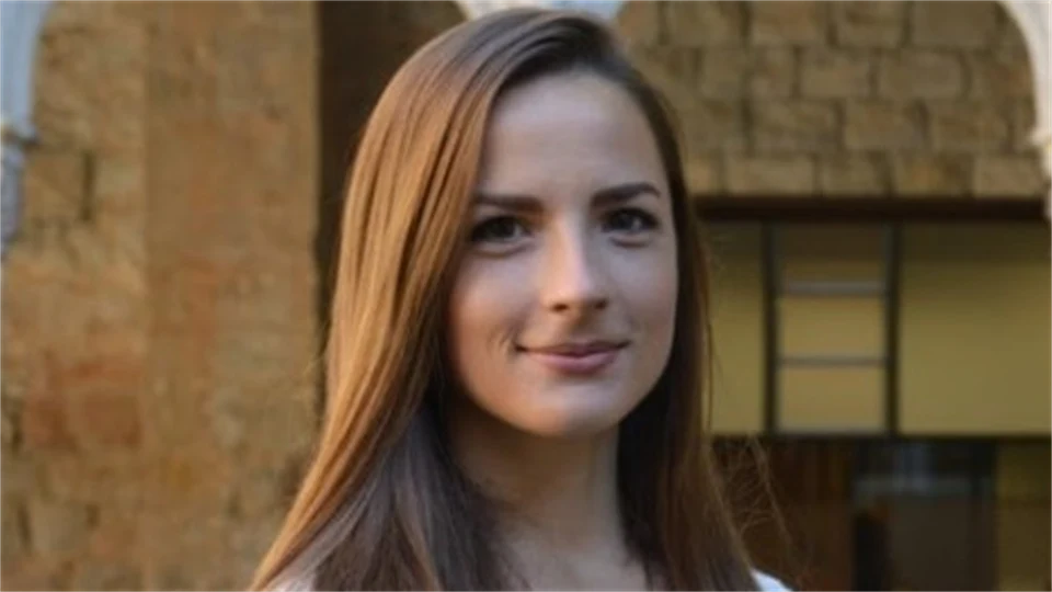 Kvinna med brunt hår ler mot kameran