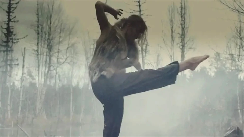 Kvinna dansar i naturen omgiven av rök