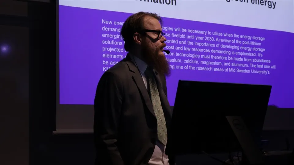 Man står framför bild med text