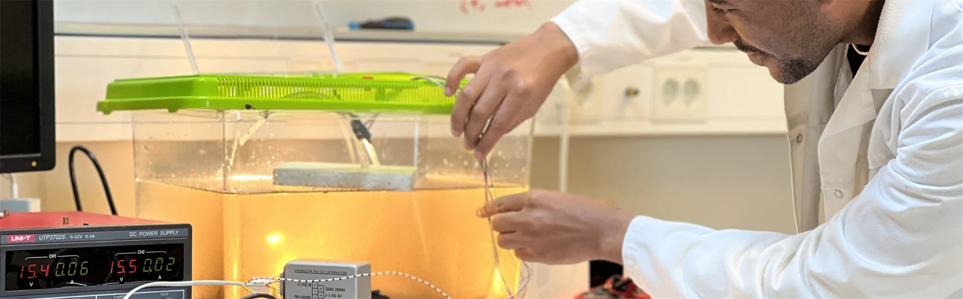 En man med labbrock arbetar med ett projekt involverande ett akvarium