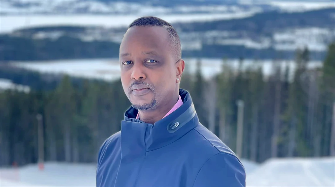 Porträtt på man utomhus med skog och fjäll i bakgrunden.