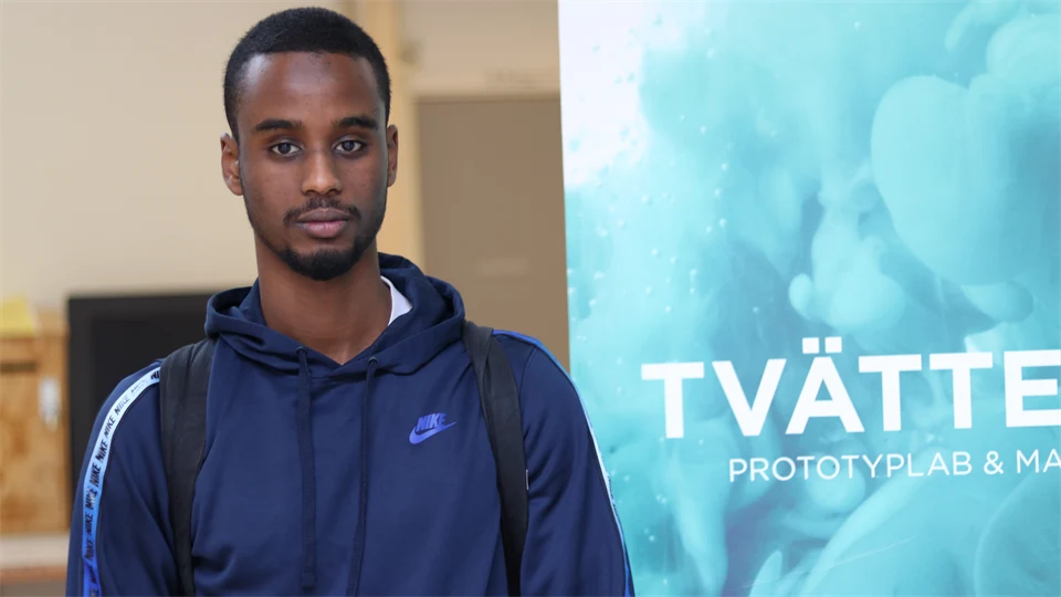 Kille i blå hoodie står framför en rollup