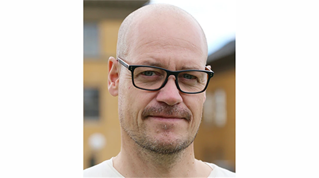 En man i svarta glasögon och rakat huvud.