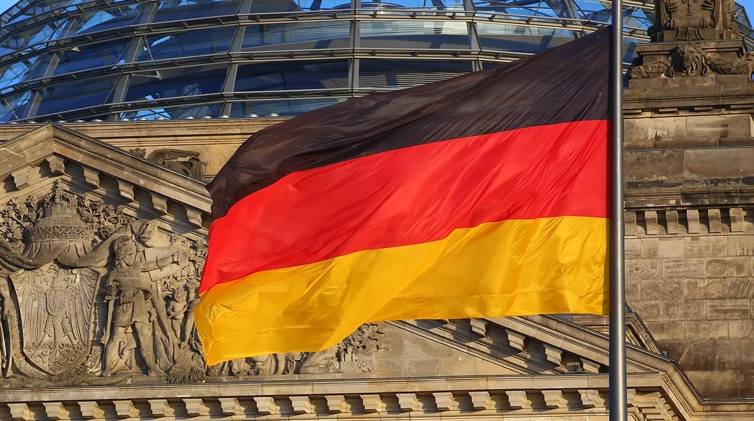Tyskflagga framför en stenfasad.