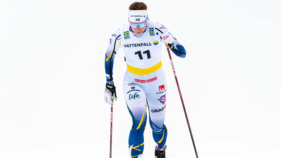 Kvinnlig längdskidåkare mot vit bakgrund.