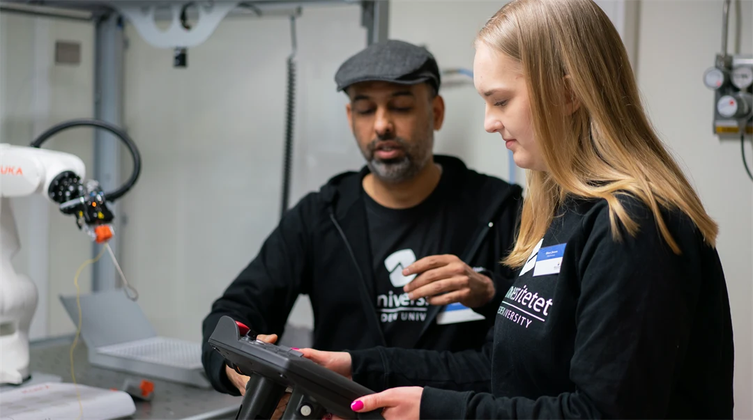 Man och kvinna som justerar en robotarm.