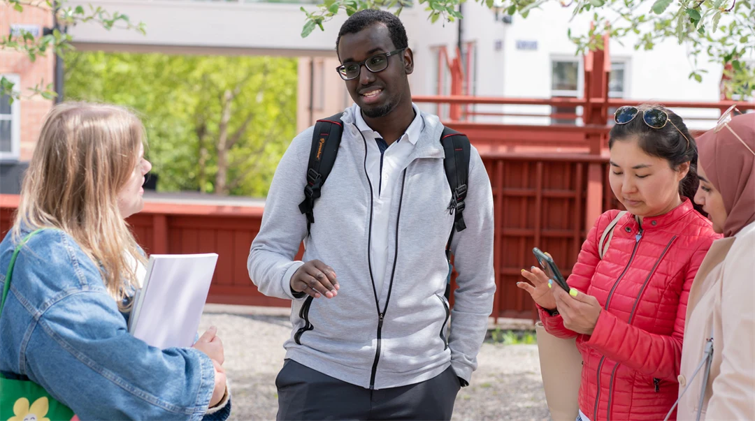 En grupp studenter som står och pratar med varandra utanför campus. 