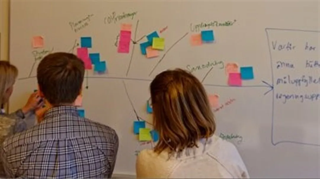 tre personer framför en whiteboardtavla